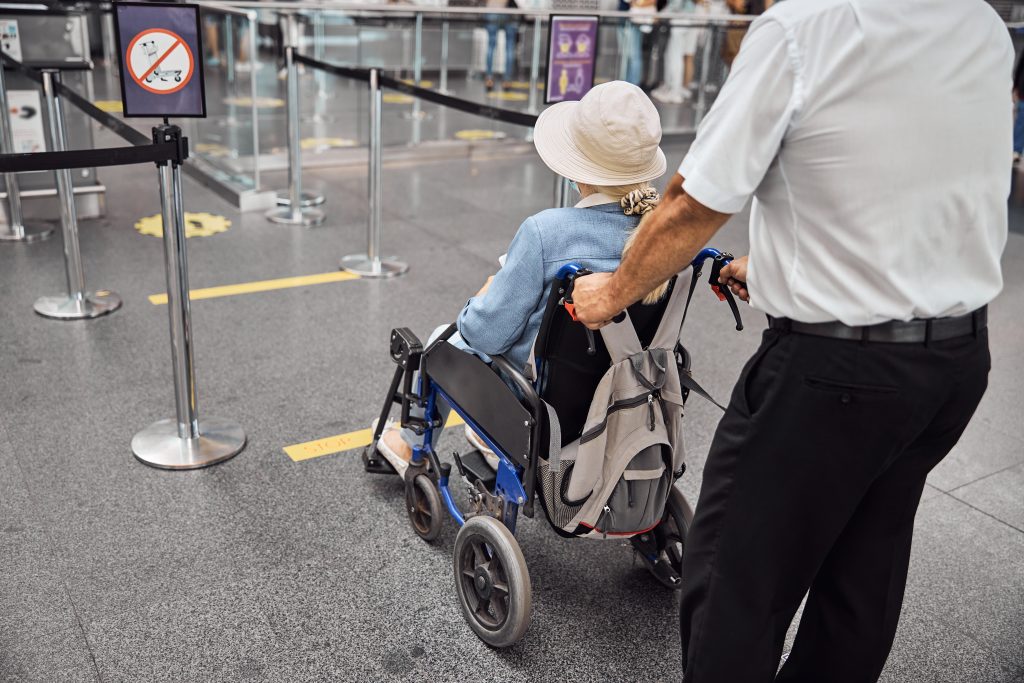 Back,View,Of,An,Airport,Male,Employee,Transporting,A,Disabled